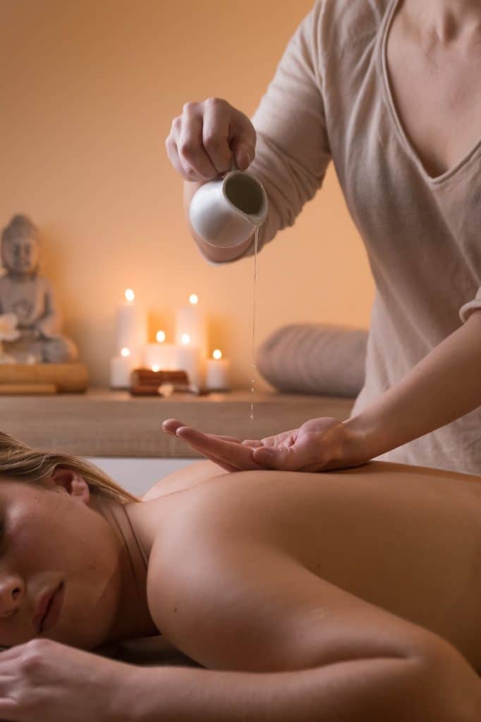 masseuse pours oil on her hand to do a massage