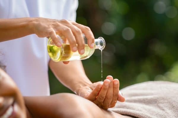 Masseuse hands pouring massage oil